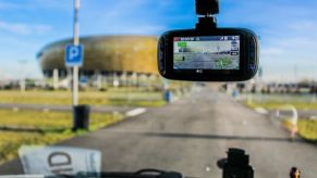 Dash cam installed on a front windshield of a car looking out onto the road ahead. In-car cameras have a lot of benefits