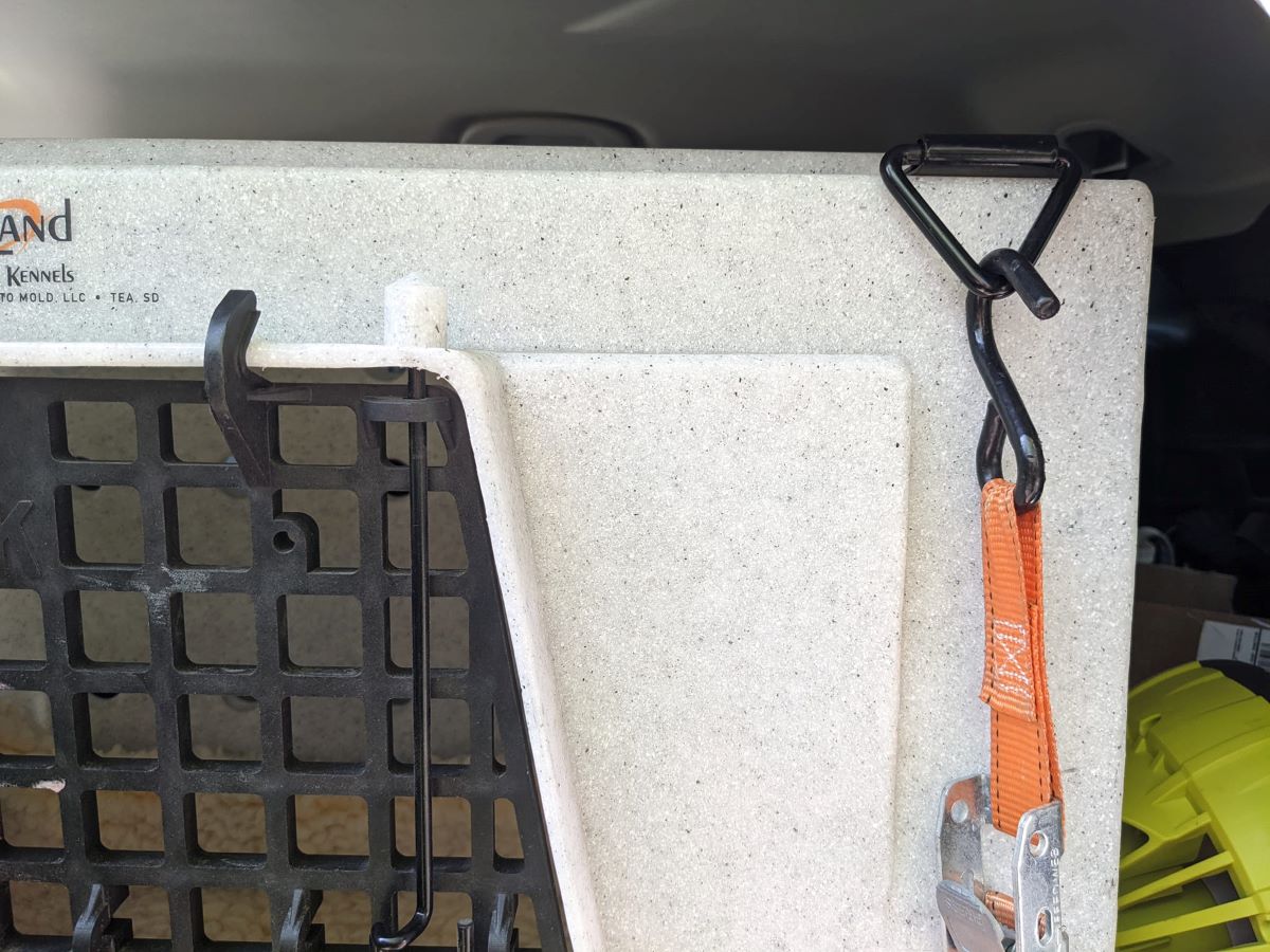 Close-up of a ratchet strap attached to a tie-down point on a car kennel