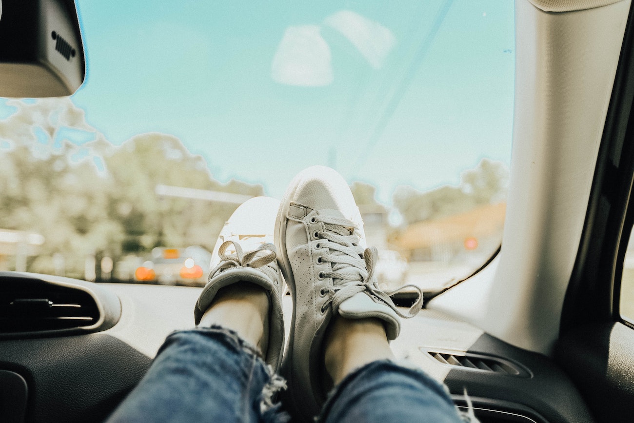 A passenger has their feet up on the car dashboard.