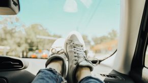 A passenger has their feet up on the car dashboard.