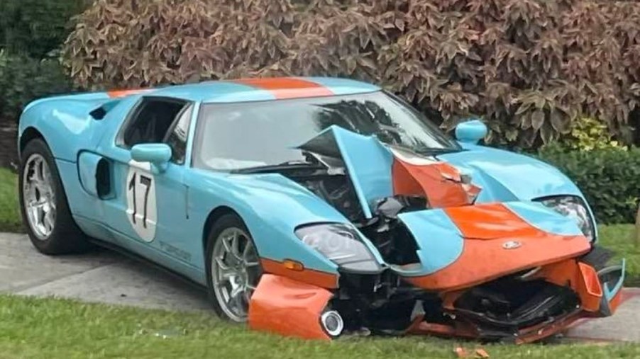 The Florida Ford GT crash. A crashed 2006 Ford GT Heritage Edition car is splayed out on the sidewalk near a stand of palm trees as passersby take pictures