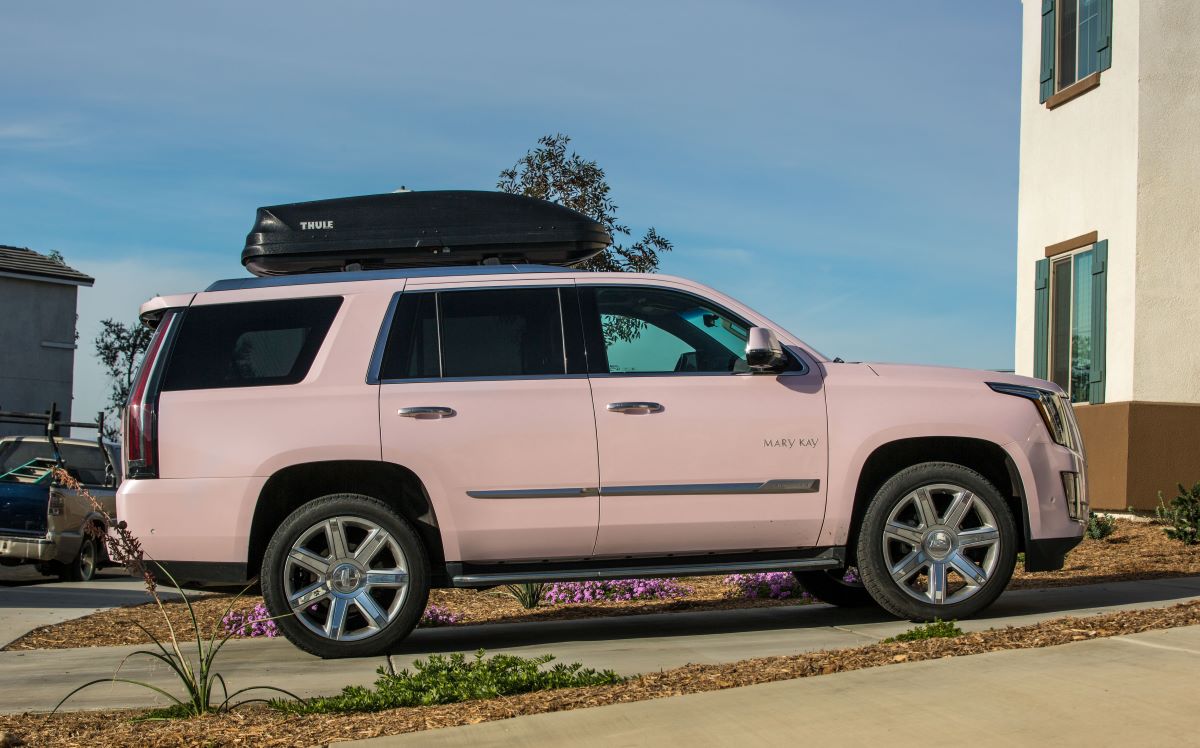A pink Cadillac Escalade parked in a neighborhood. Free MLM cars like these can come with a lot of strings attached