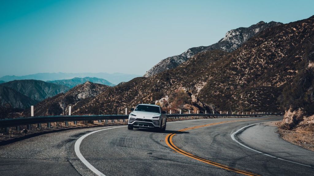 A white Lamborghini Urus drives along the curved roads of the Angeles Crest Highway on the way to the Good Vibes Breakfast Club