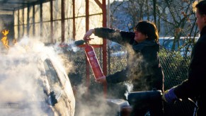 A man puts out a car fire with an extinguisher.