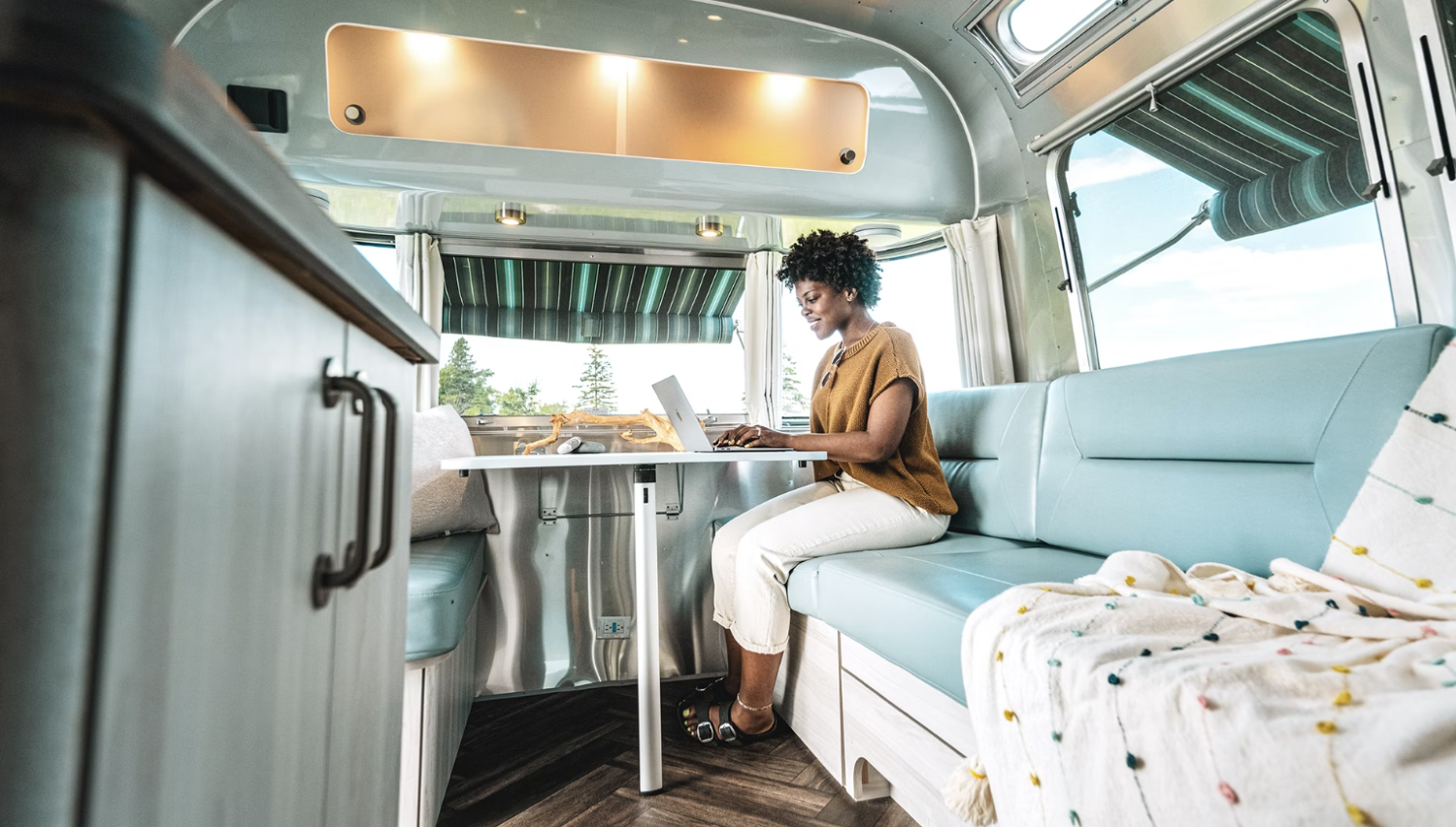 A woman working on a laptop inside an Airstream RV