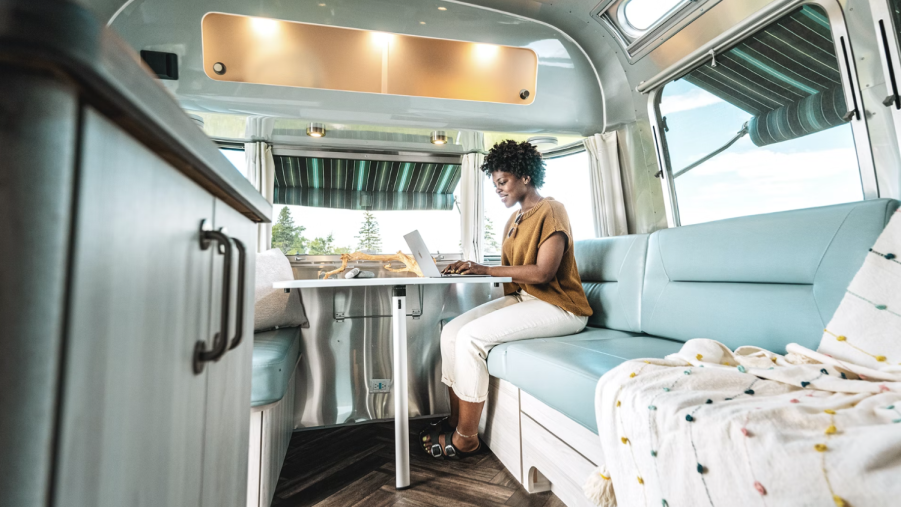 A woman working on a laptop inside an Airstream RV