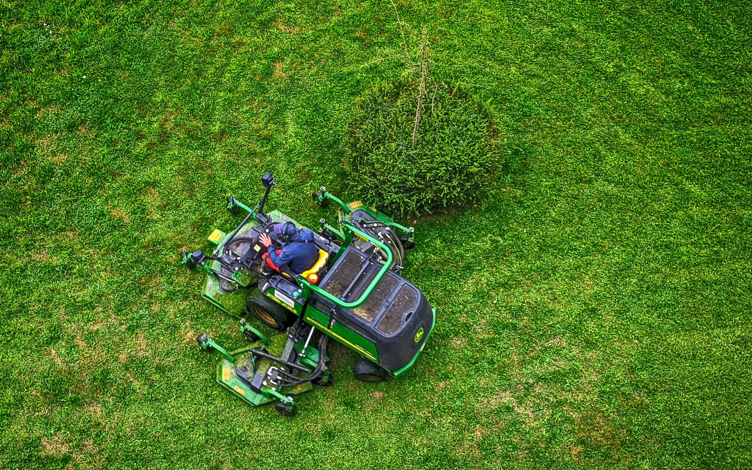 A man mows grass on his John Deere ride-on lawn mower.