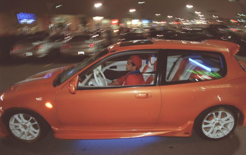 Matala oranssi Honda Civic ajaa parkkipaikan läpi.