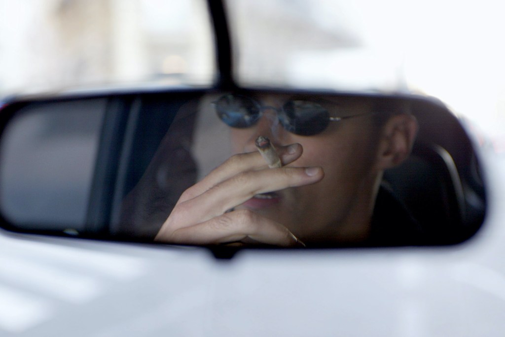 Man smoking a cigarette in a car mirror