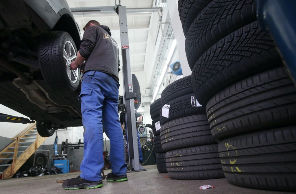 A mechanic changes tires on a car.