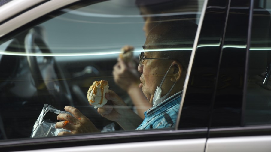 Two men eat their take away food inside a car.