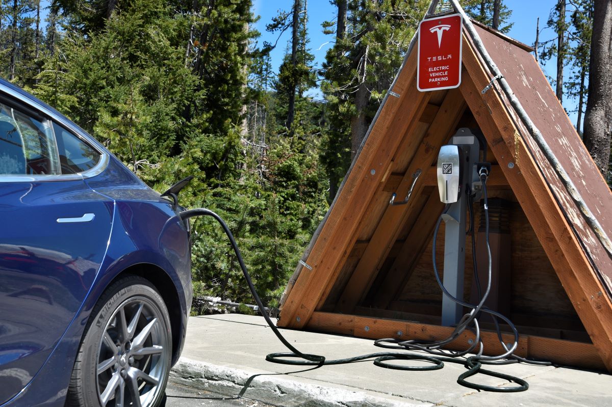 Blue Tesla parked and charging near a covered EV charging station; EVs in  mild climates are more reliable used electric cars