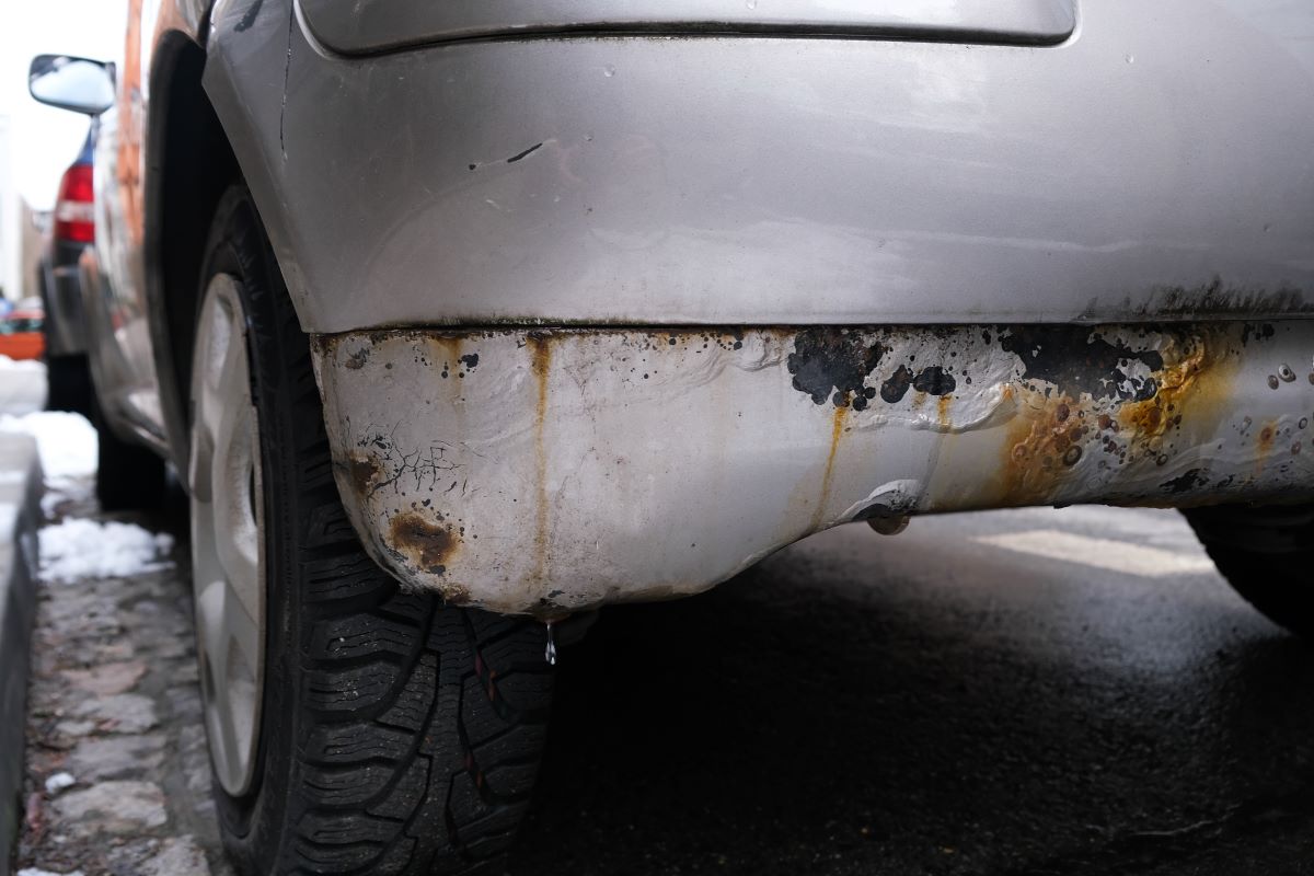 Close up of the rusted rear bumper of a white car.  Choose one of the best rust removers to solve rust problems in your car