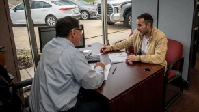 A car salesperson talks to a customer at his desk