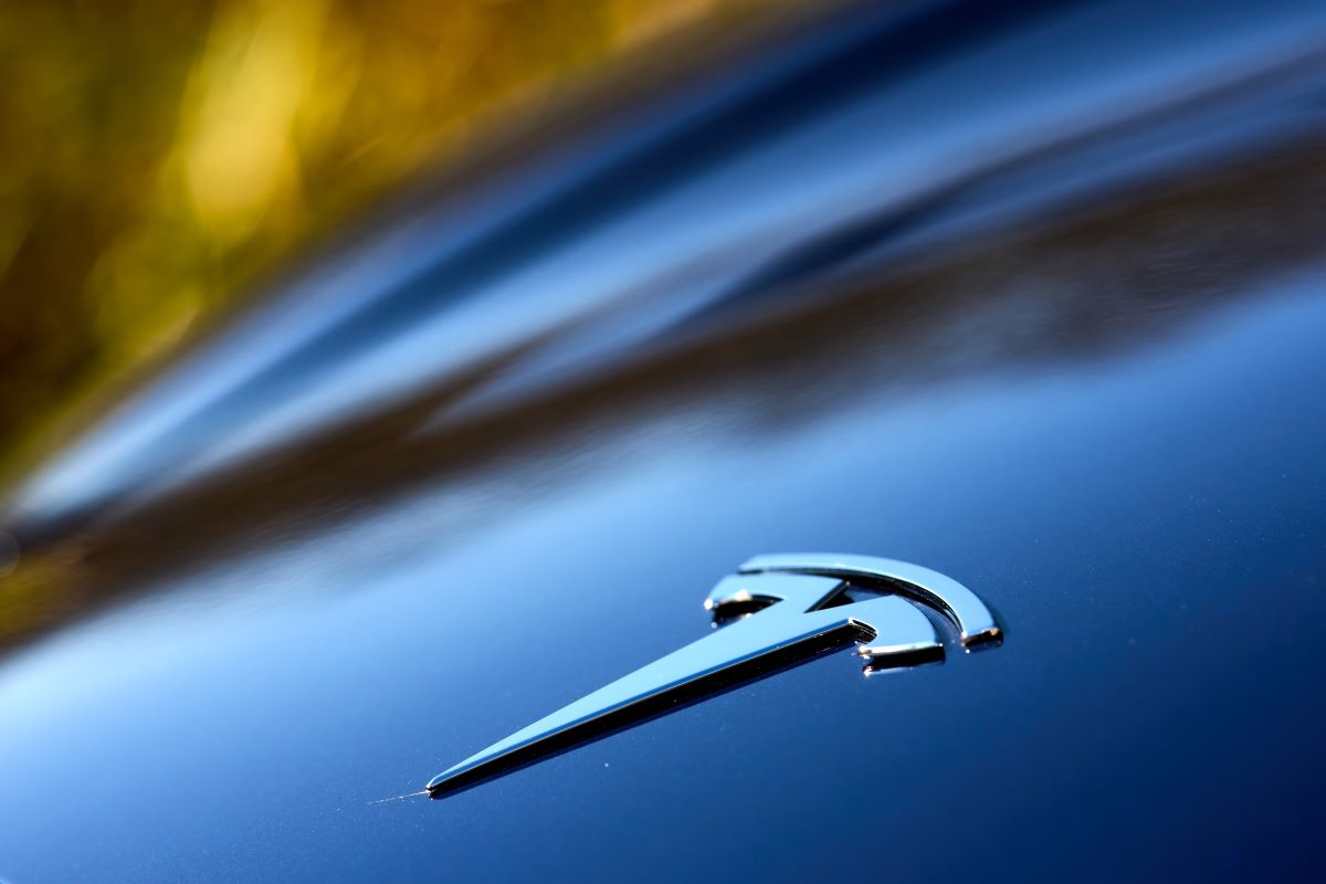 Close-up of a Tesla logo on a blue car; Tesla has hit its EV tax credit limit