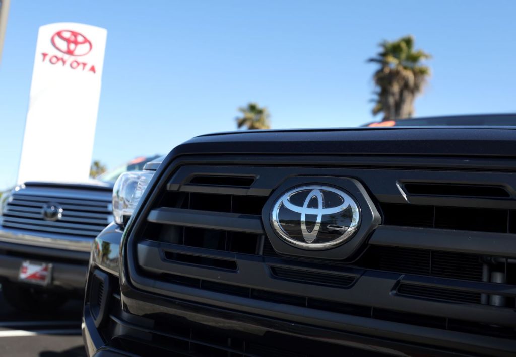Close up of a Toyota logo on a truck's grille at a Toyota dealership, where you could go if your Toyota maintenance light is on