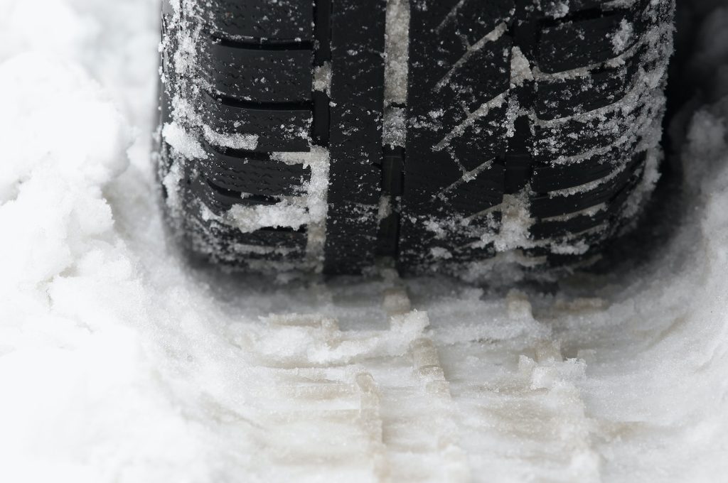 A snow tire making a track in the snow.