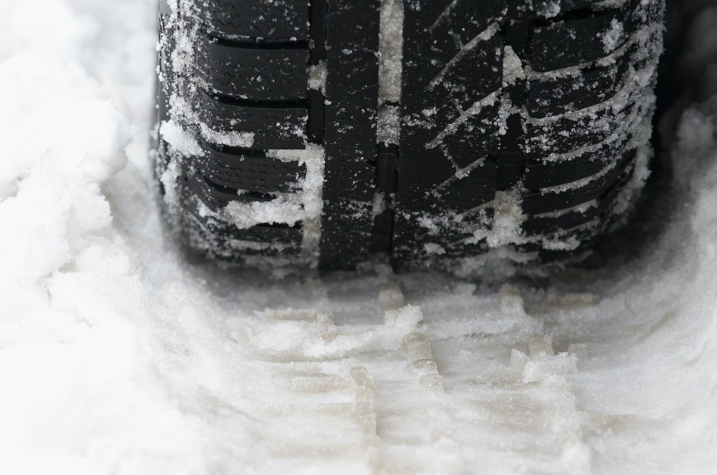 A snow tire making a track in the snow.