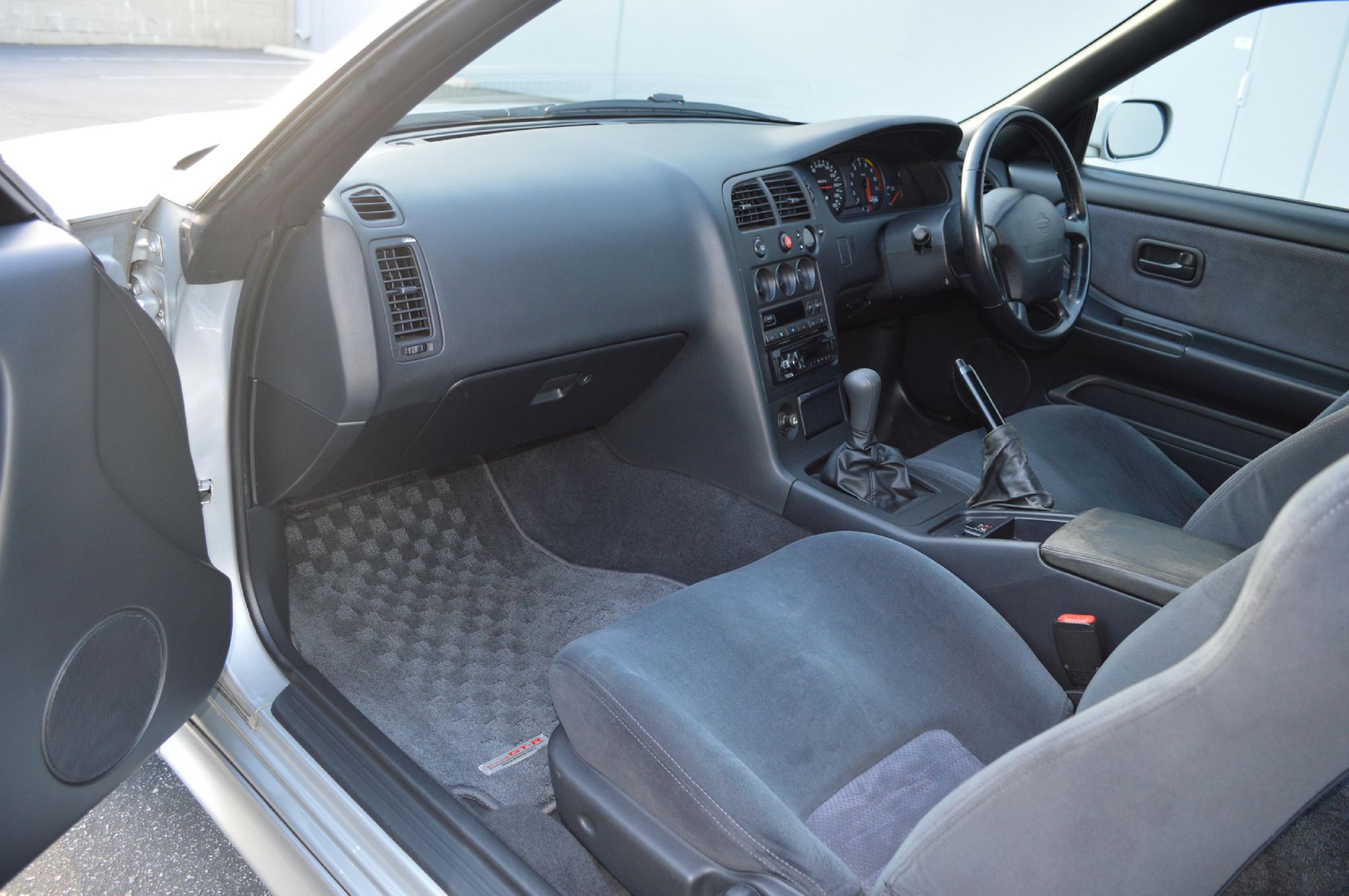 The gray front sports seats and black dashboard of a 1995 Nissan R33 Skyline GT-R