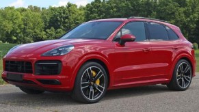 A red 2022 Porsche Cayenne in front of trees.