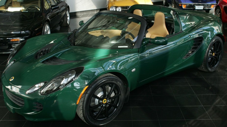 a green 2005 lotus elise sitting in a show room with two seats waiting to be purchased