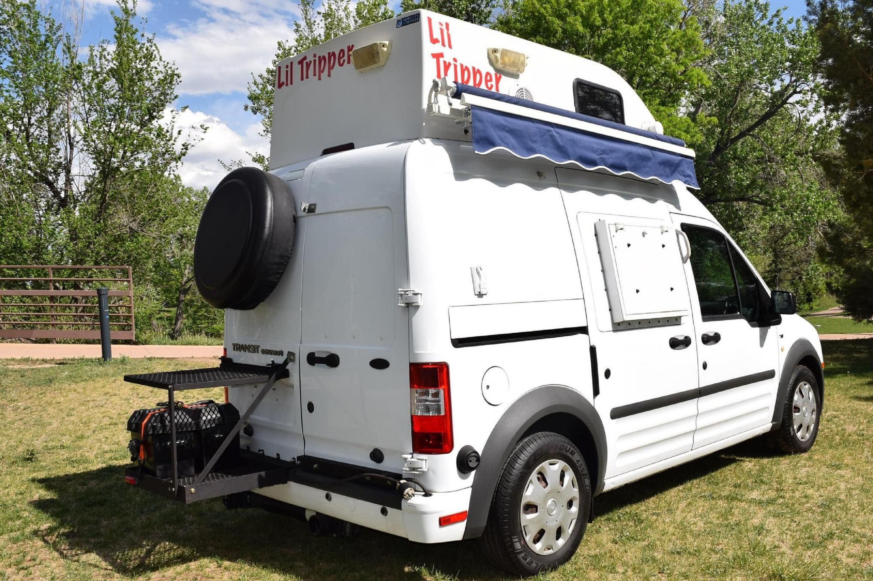 Rear view of white 2011 Ford Transit Connect XLT 3/4 camper van with external battery and spare tire