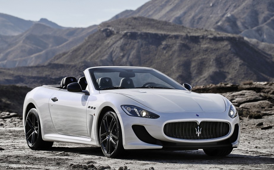 A white 2013 Maserati GranTurismo MC Cabriolet with the top down parked on top of a mountain