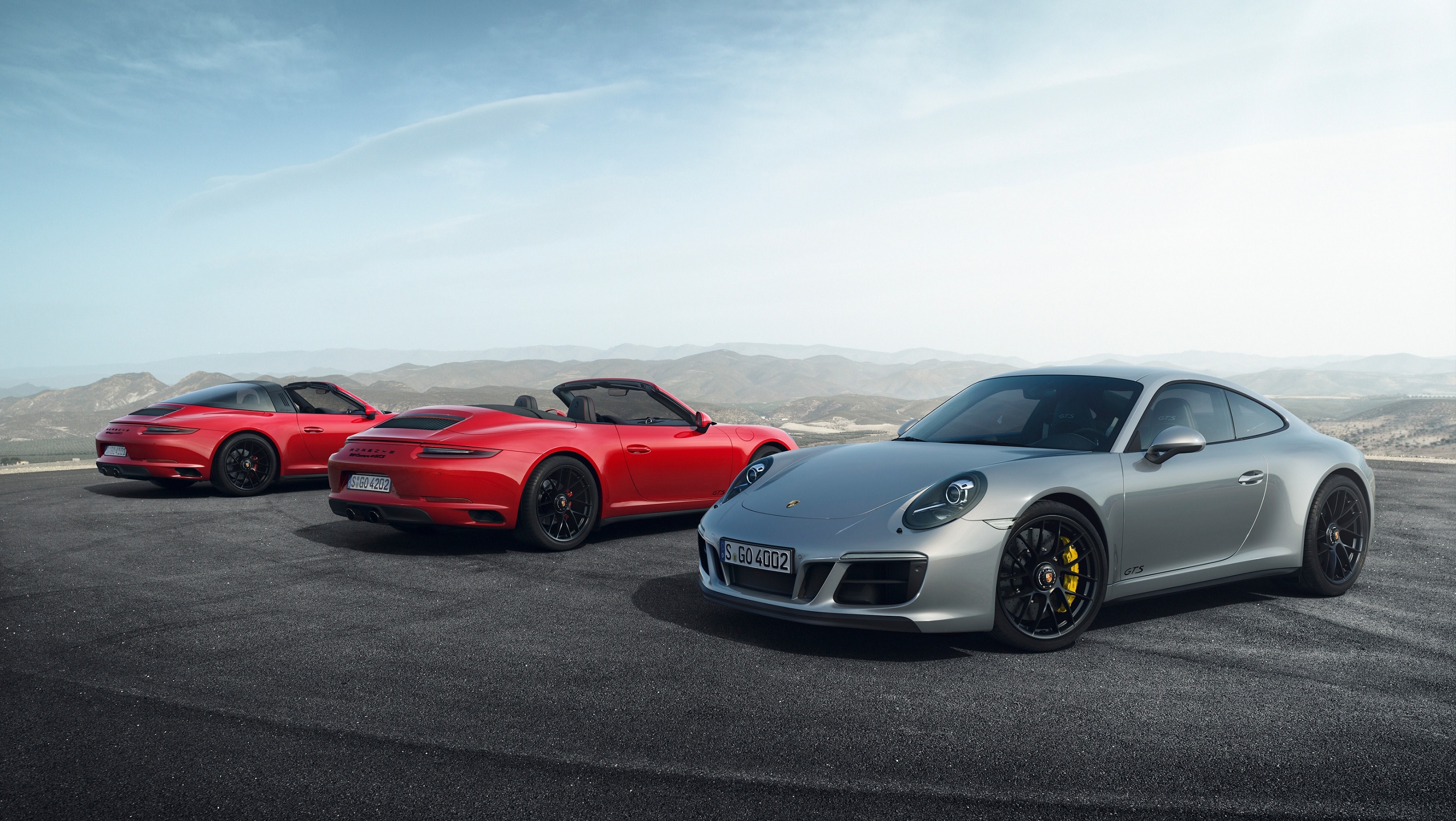 From left to right, a red 2017 Porsche 991.2 911 Targa 4 GTS, red Carrera 4 GTS Cabriolet, and silver Carrera 4 GTS