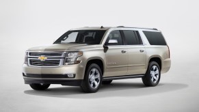 A gold 2017 Chevy Suburban against a beige background.