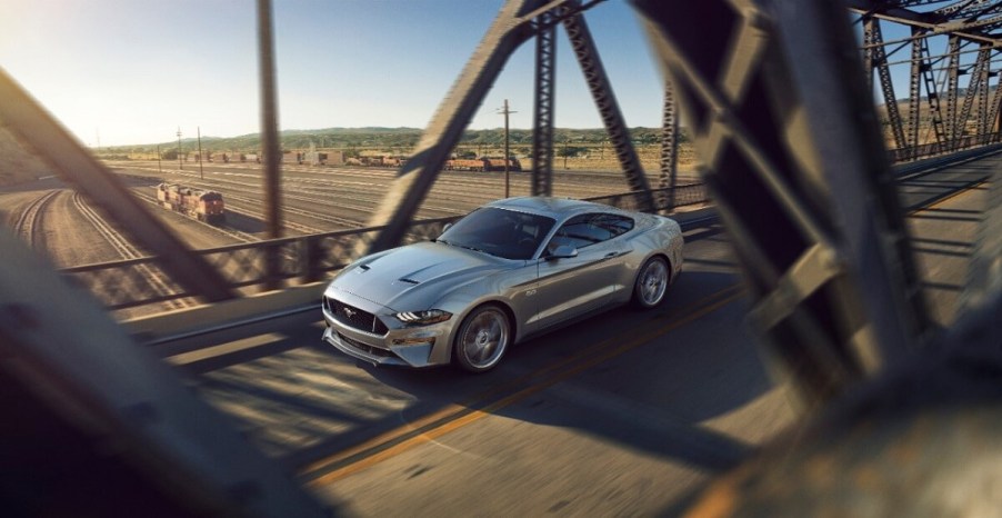 A staple among cheap fast cars, a 2018 Ford Mustang GT cruises across a bridge.