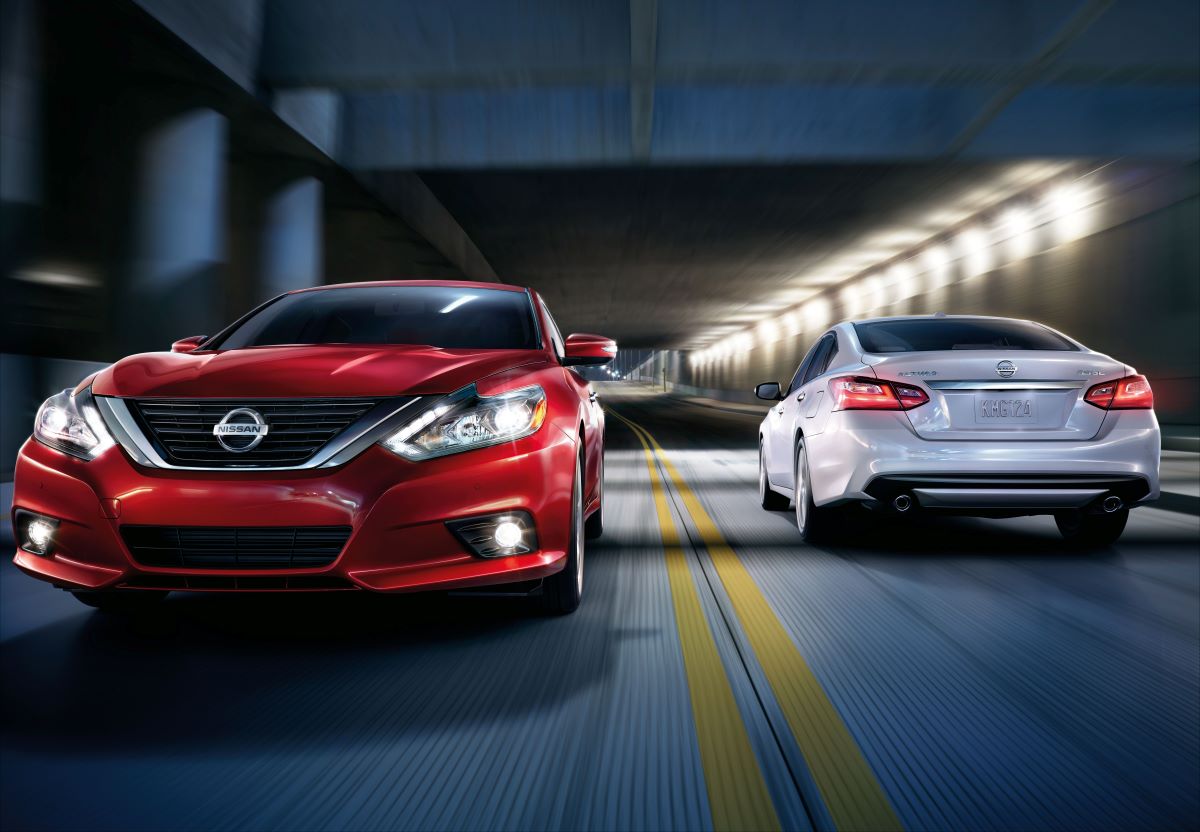 Two 2018 Nissan Altima sedans, one red and one white, driving in separate directions