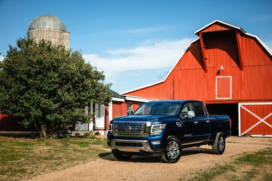 Promo photo of a Nissan Titan XD parked in front of a bright red barn.