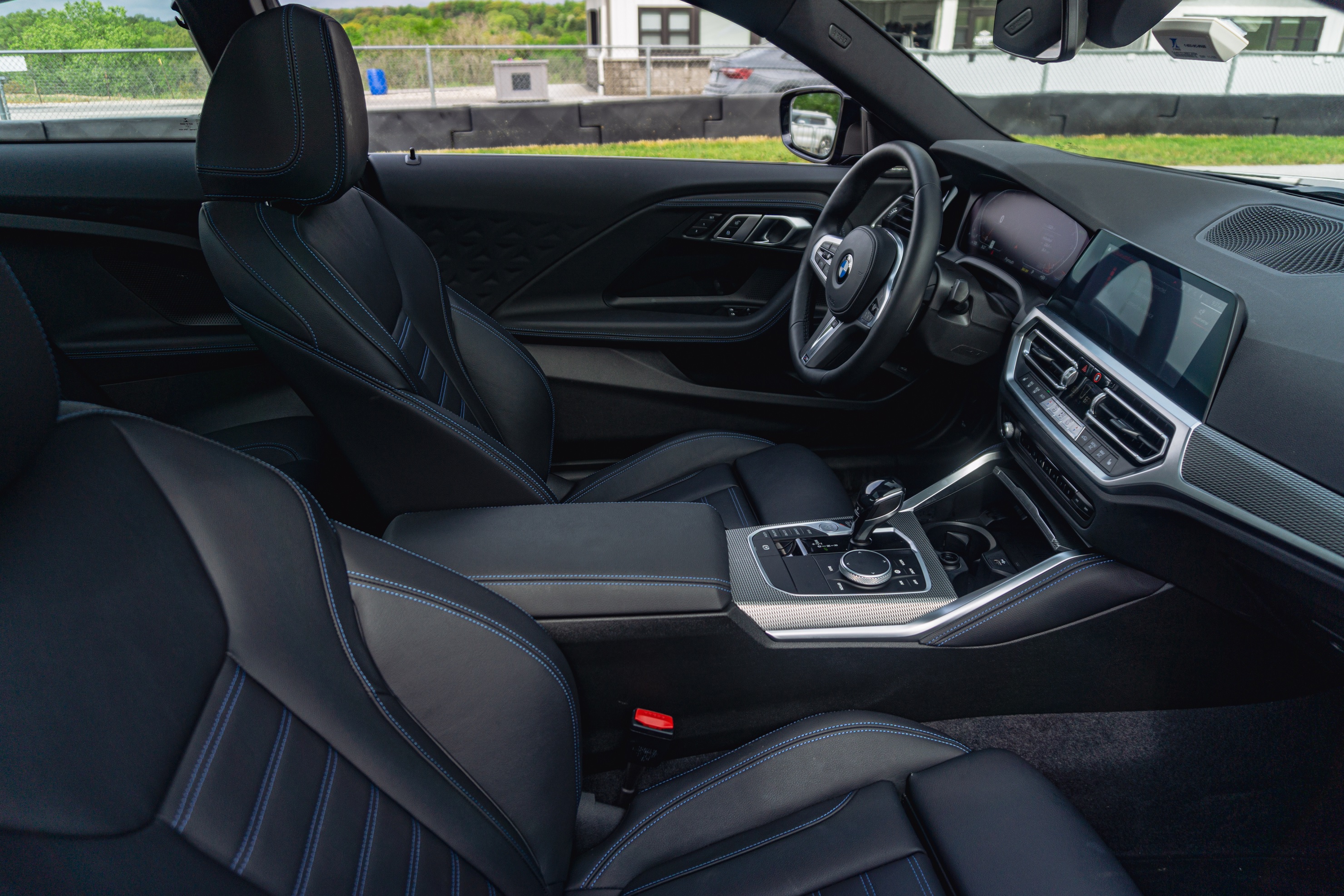 The black-leather front sports seats and black dashboard of a 2022 BMW M240i xDrive Coupe