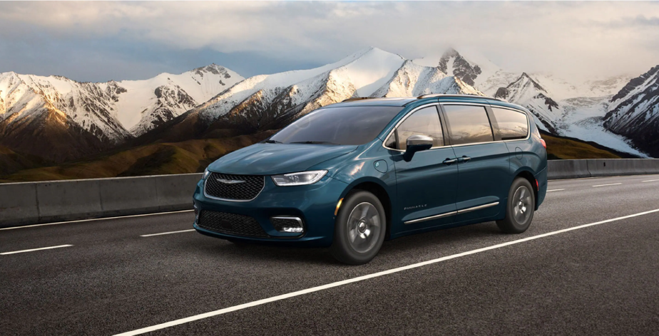 A 2022 Chrysler Pacifica Hybrid Pinnacle minivan with in Fathom Blue Pearl driving on a snowy mountain highway
