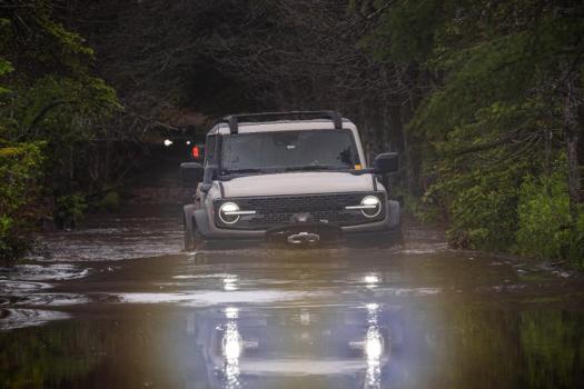A Ford Bronco driving through a deep puddle.