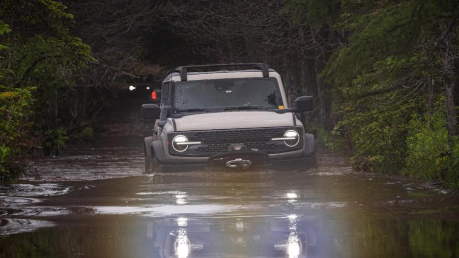 A Ford Bronco driving through a deep puddle.