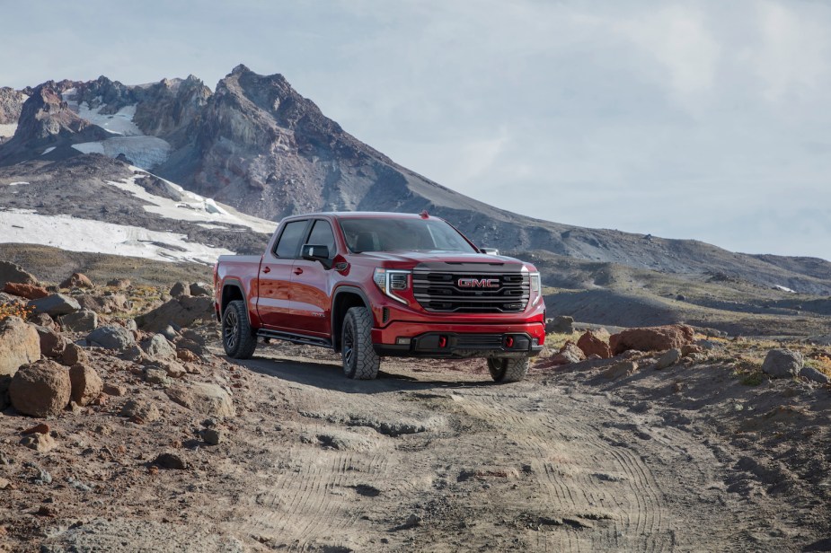 Red GMC Sierra 4x4 off-roading with mountains in the background.