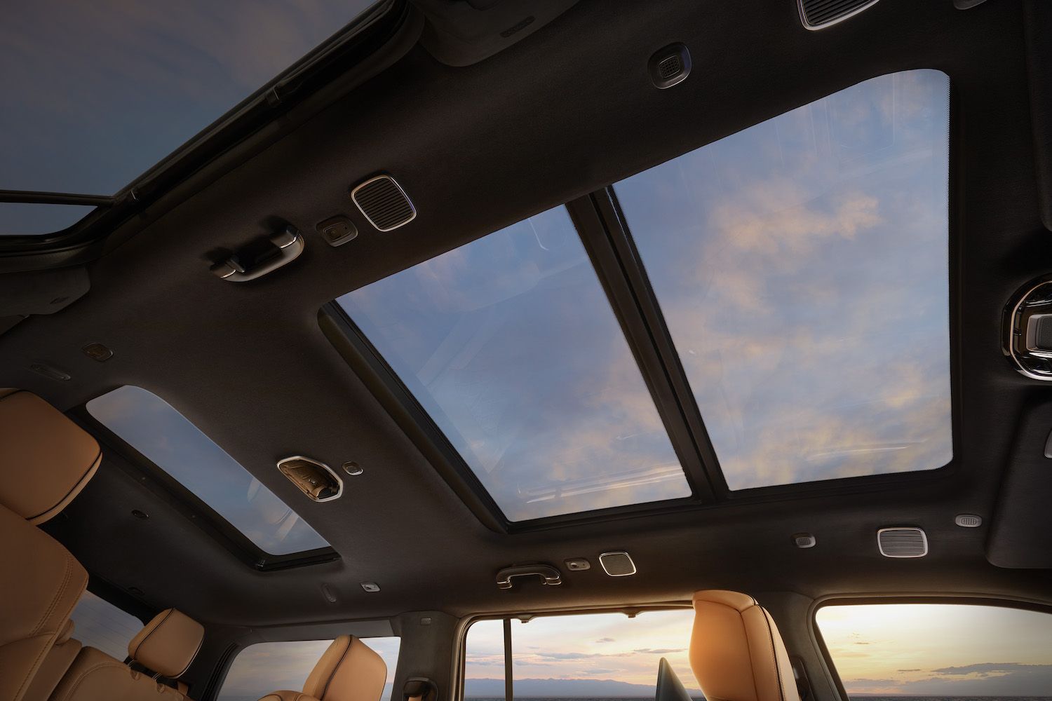 Pink clouds visible through the sunroof of a Jeep Grand Wagoneer luxury SUV.
