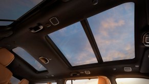 Pink clouds visible through the sunroof of a Jeep Grand Wagoneer luxury SUV.