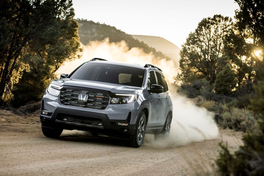 A 2022 Honda Passport Trailsport SUV model driving on a dirt trail as a cloud of kicked up dirt and dust trails it