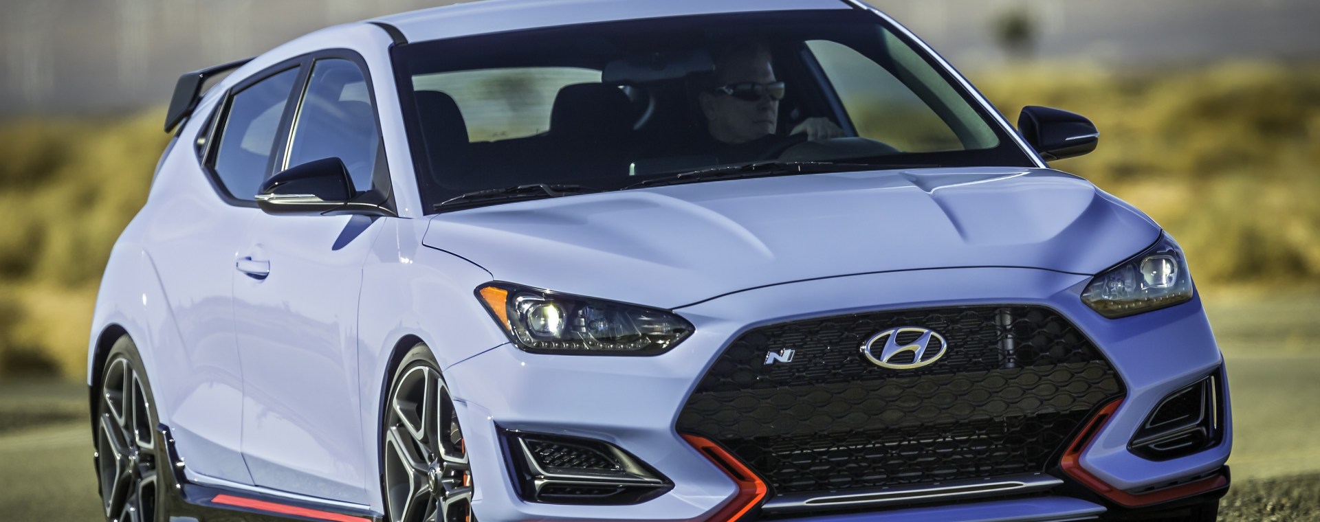 A light-blue 2022 Hyundai Veloster N cornering on a desert racetrack