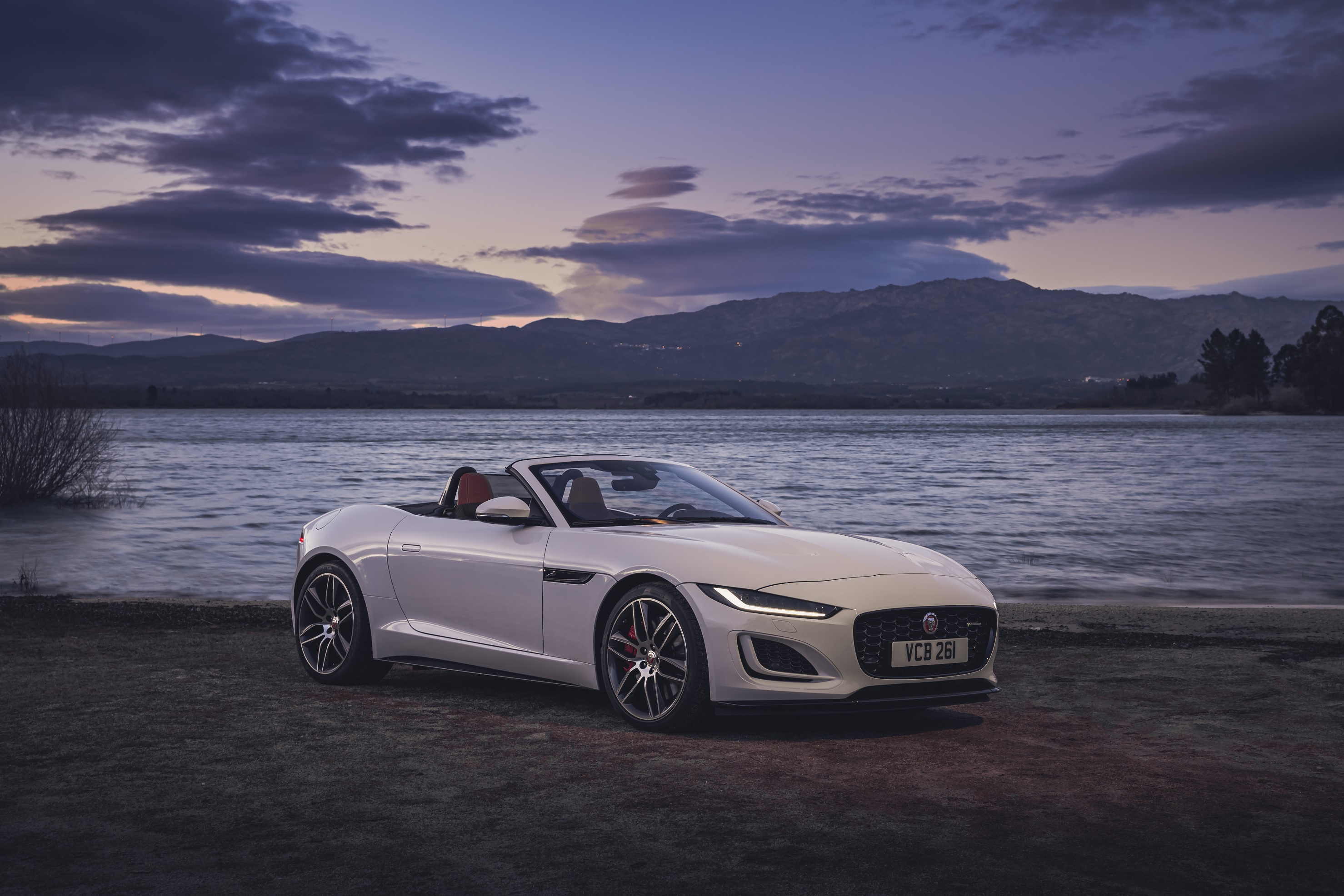 A white 2022 Jaguar F-Type Convertible P450 in front of a body of water with the roof down