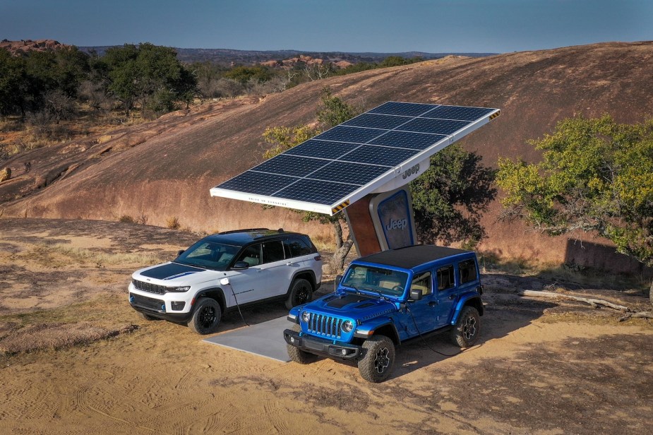 Release photo of Jeep's plug-in hybrid Grand Cherokee and Wrangler charging together, in the desert, from a solar panel.