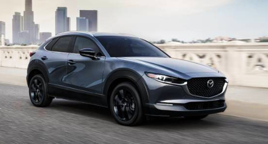 A gray 2022 Mazda CX-30 subcompact SUV is driving on the road.