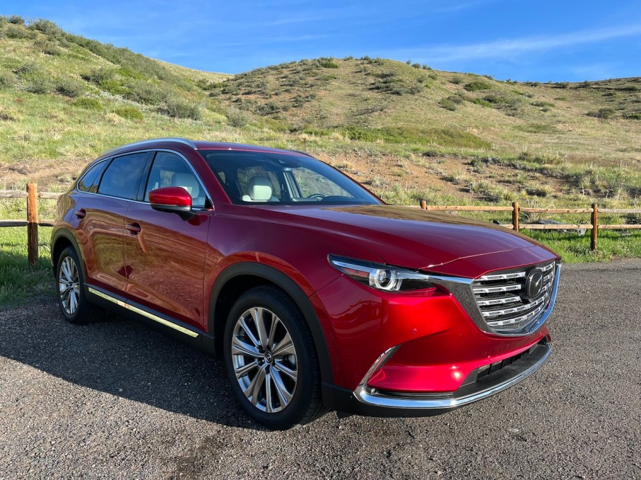 The Soul Red 2022 Mazda CX-9 parked near a hill.