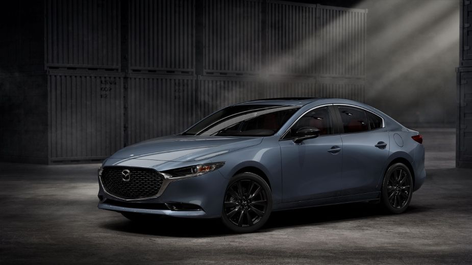 A sky blue 2022 Mazda3, possibly with a manual transmission, parked in a slightly lit environment.