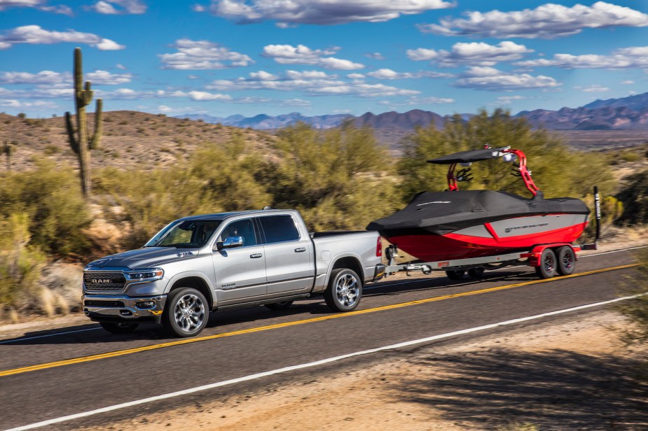 Silver V8 Ram pickup truck towing a boat through the desert.