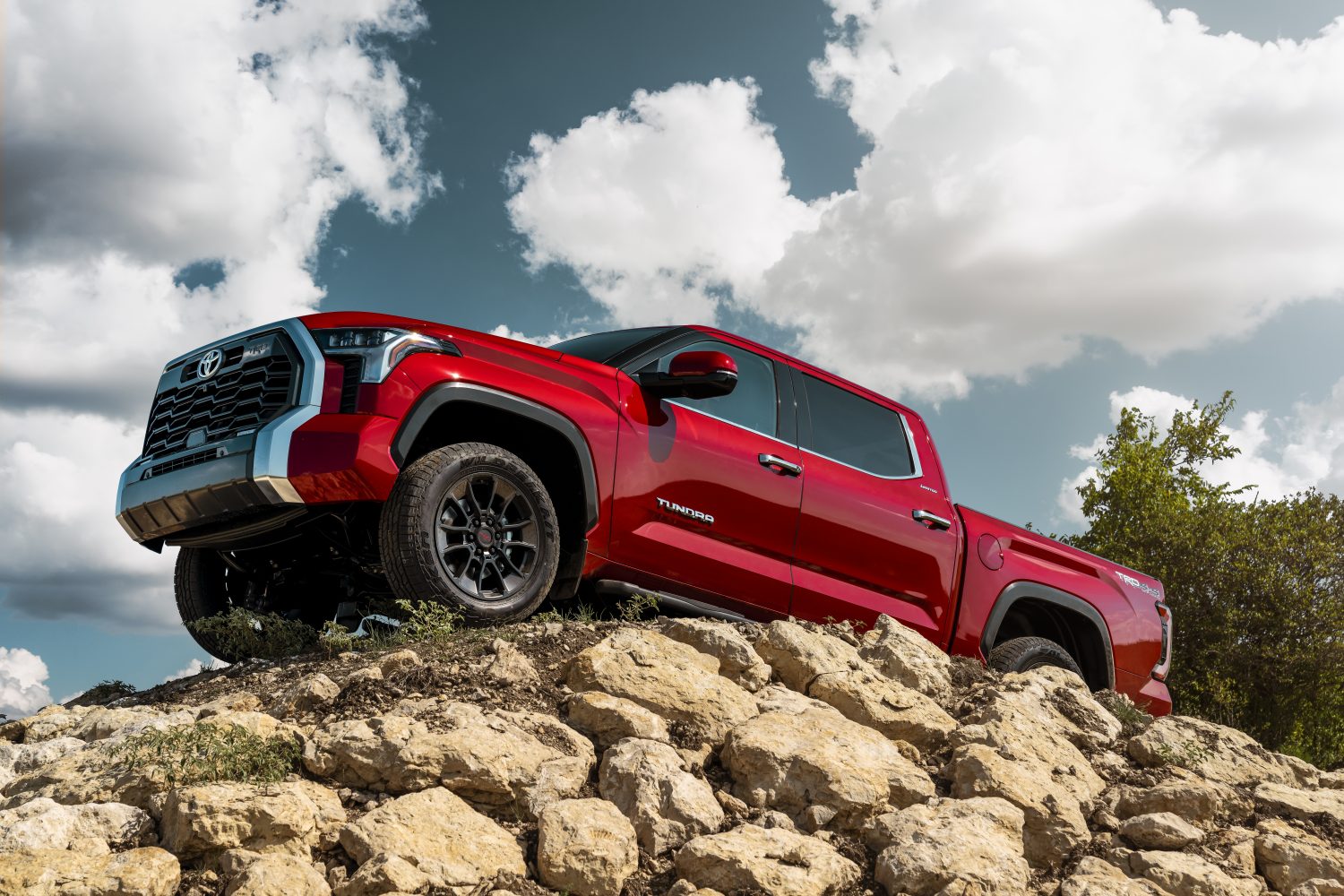 Red Toyota Tundra pickup truck shows off its TRD Off-Road package by parking atop a pile of rocks.