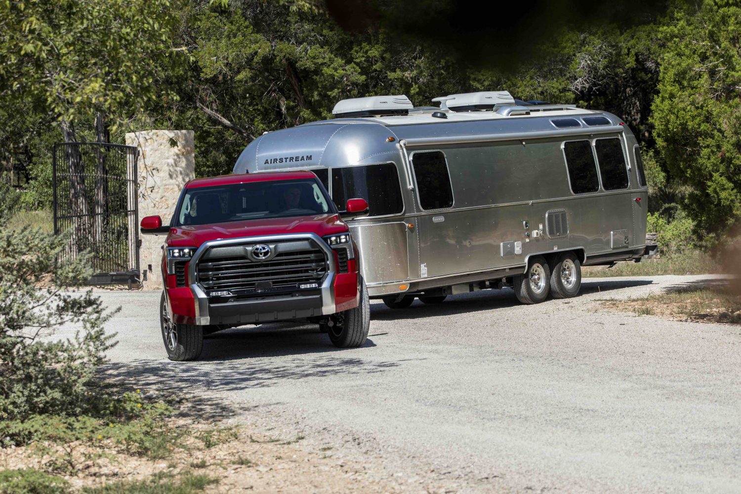 Red Toyota Tundra pickup truck demonstrating its towing capacity by pulling a camper trailer.