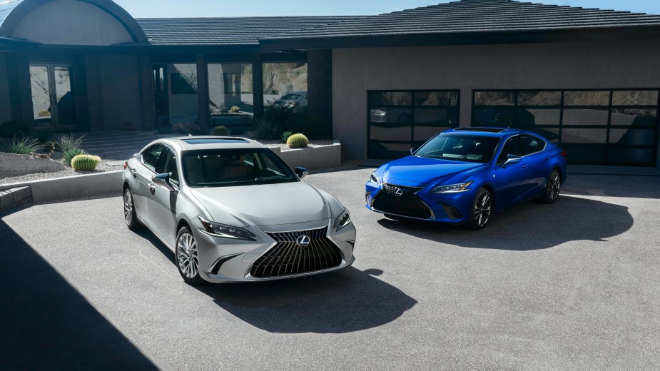 A silver 2022 Lexus ES parked beside a blue 2022 Lexus ES in the driveway of an upscale home.